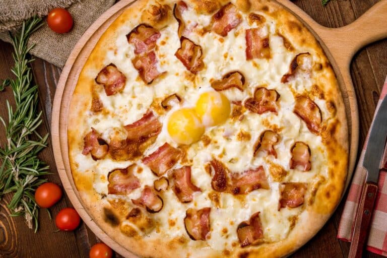 Pizza au bacon et œufs sur planche.