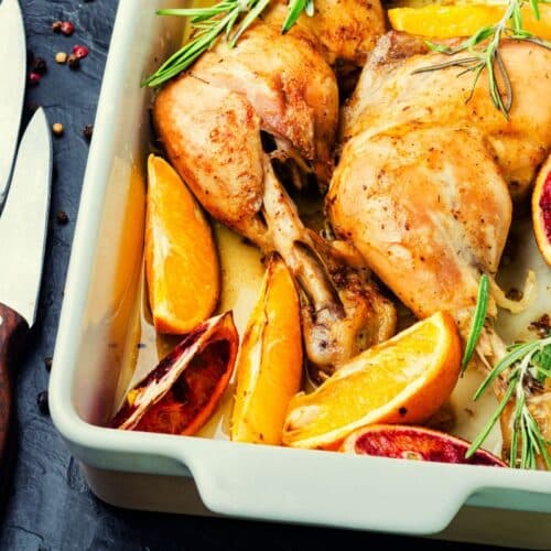 Poulet rôti avec agrumes et romarin dans un plat.