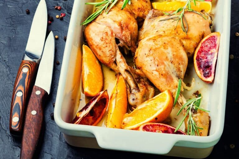 Poulet rôti avec agrumes et romarin dans un plat.