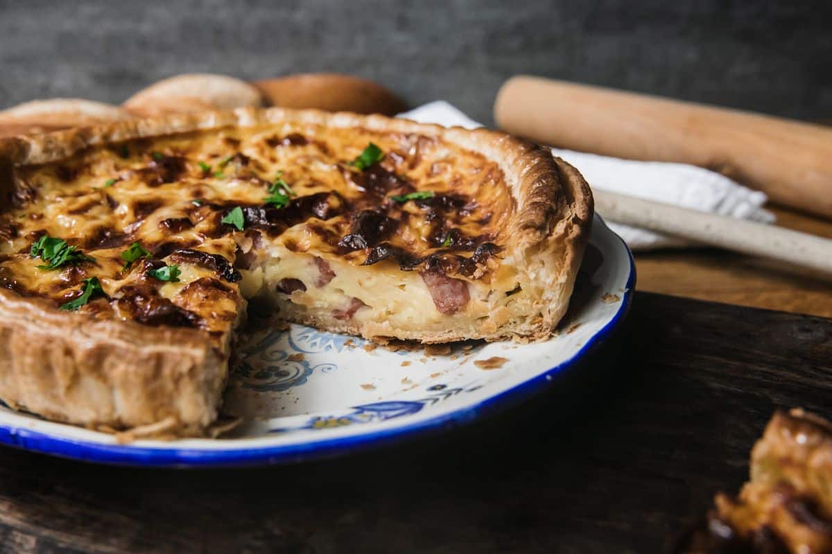 Quiche lorraine dans une assiette décorative, part retirée.