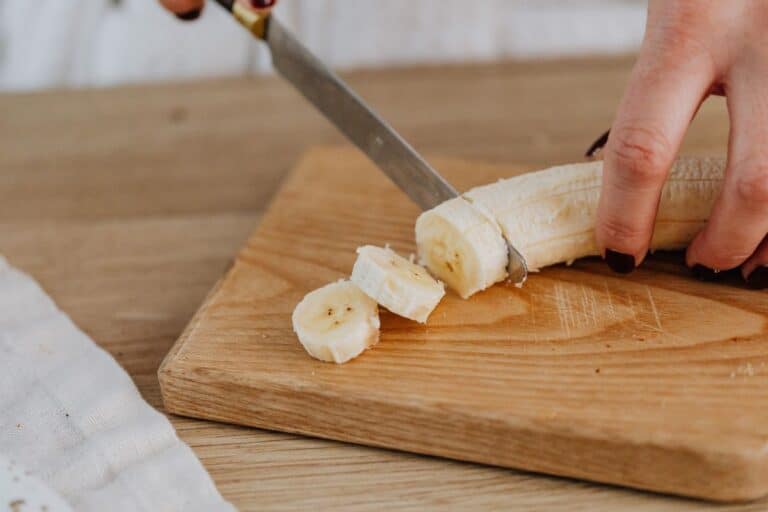 Personne coupant une banane sur une planche.