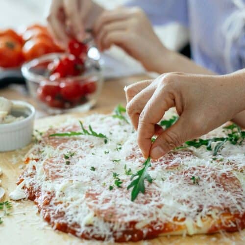 Préparation de pizza avec roquette et fromage râpé.