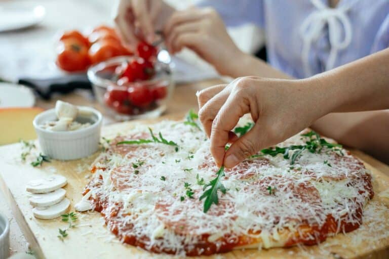 Préparation de pizza avec roquette et fromage râpé.