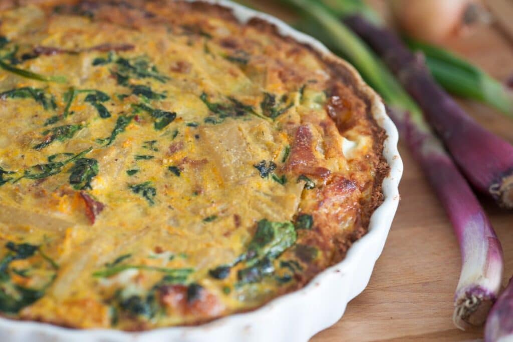Quiche aux épinards et oignons sur planche bois.