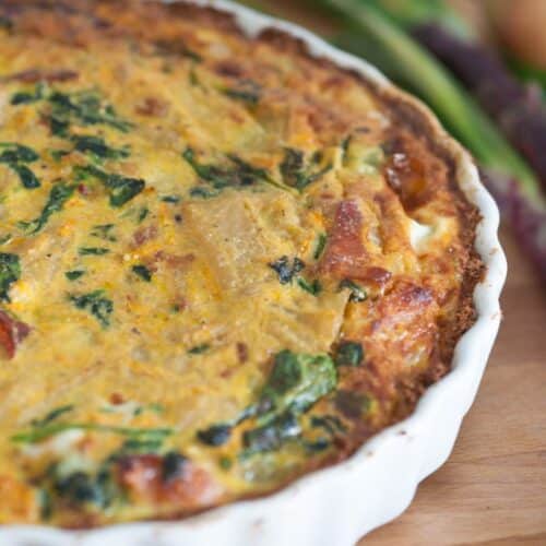 Quiche aux épinards et oignons sur planche bois.