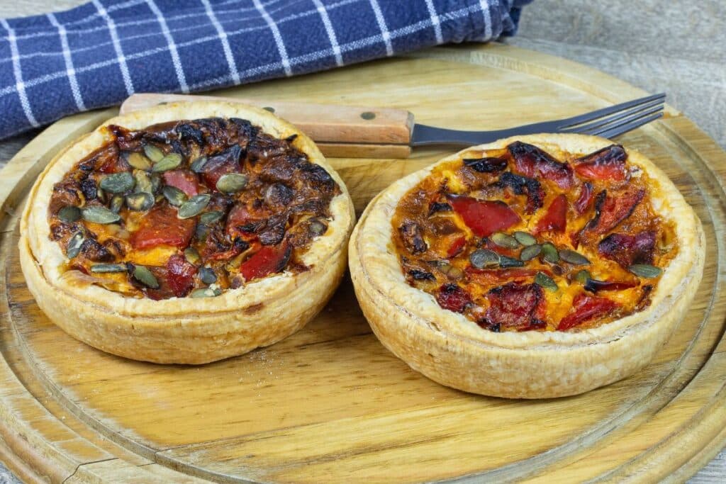 Deux tartes aux légumes et graines sur planche.