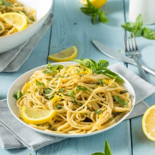 Spaghettis au citron et basilic sur assiette blanche.