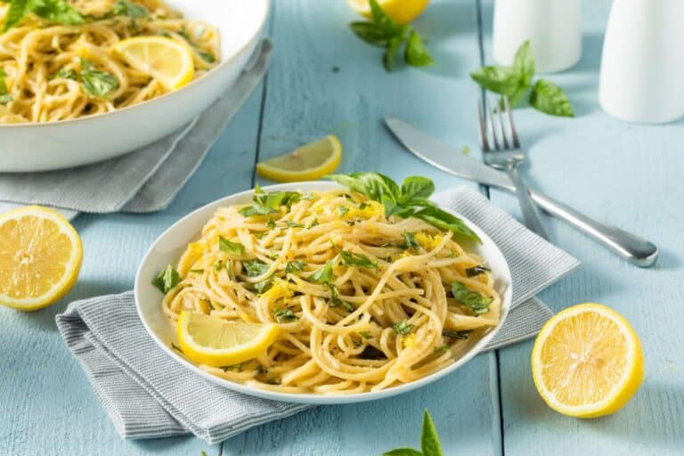 Spaghettis au citron et basilic sur assiette blanche.