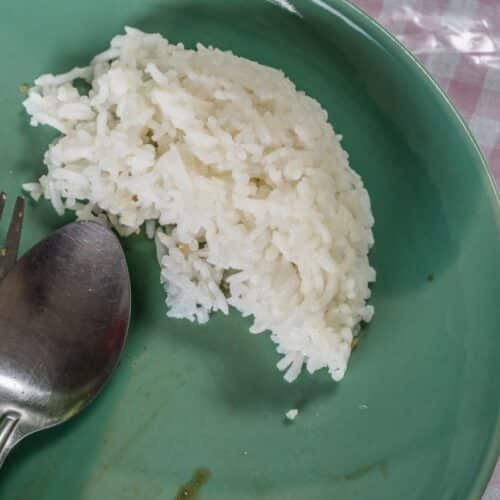 Assiette verte avec riz et couverts.