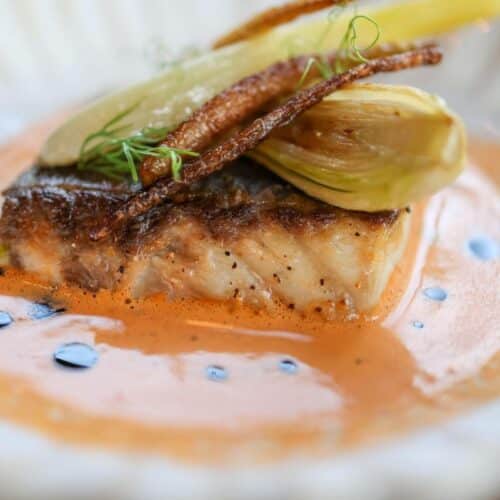 Plat de poisson avec légumes et sauce crémeuse.