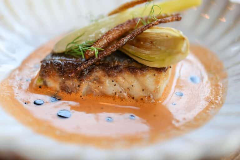 Plat de poisson avec légumes et sauce crémeuse.