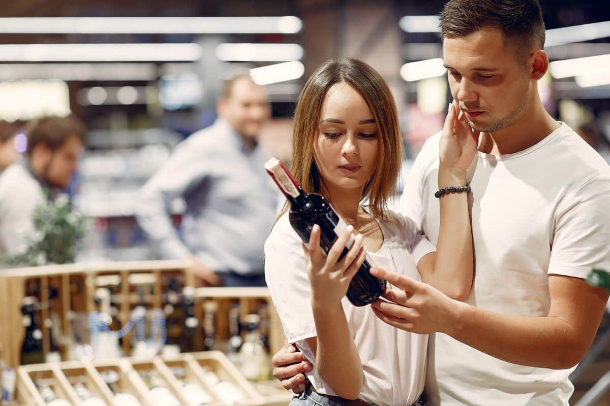 Couple choisissant une bouteille de vin en magasin.