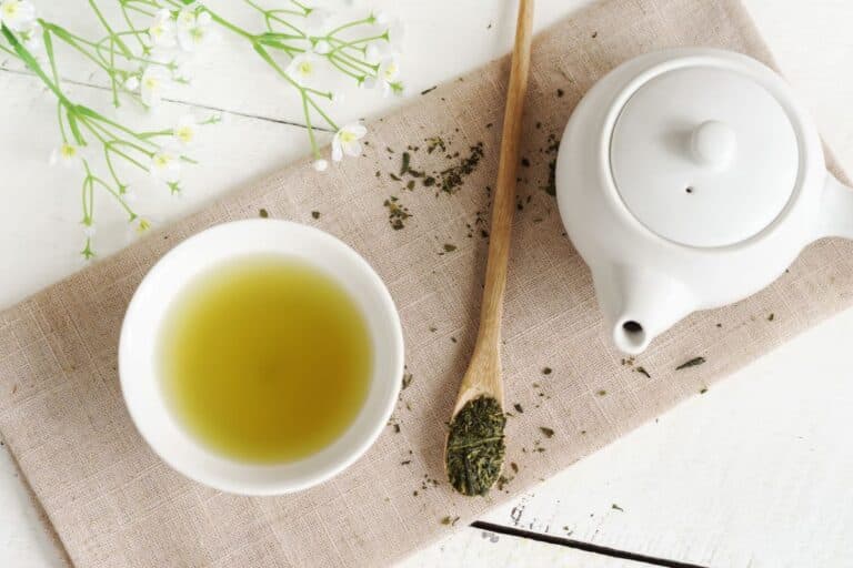 Tasse de thé vert et théière en porcelaine blanche.