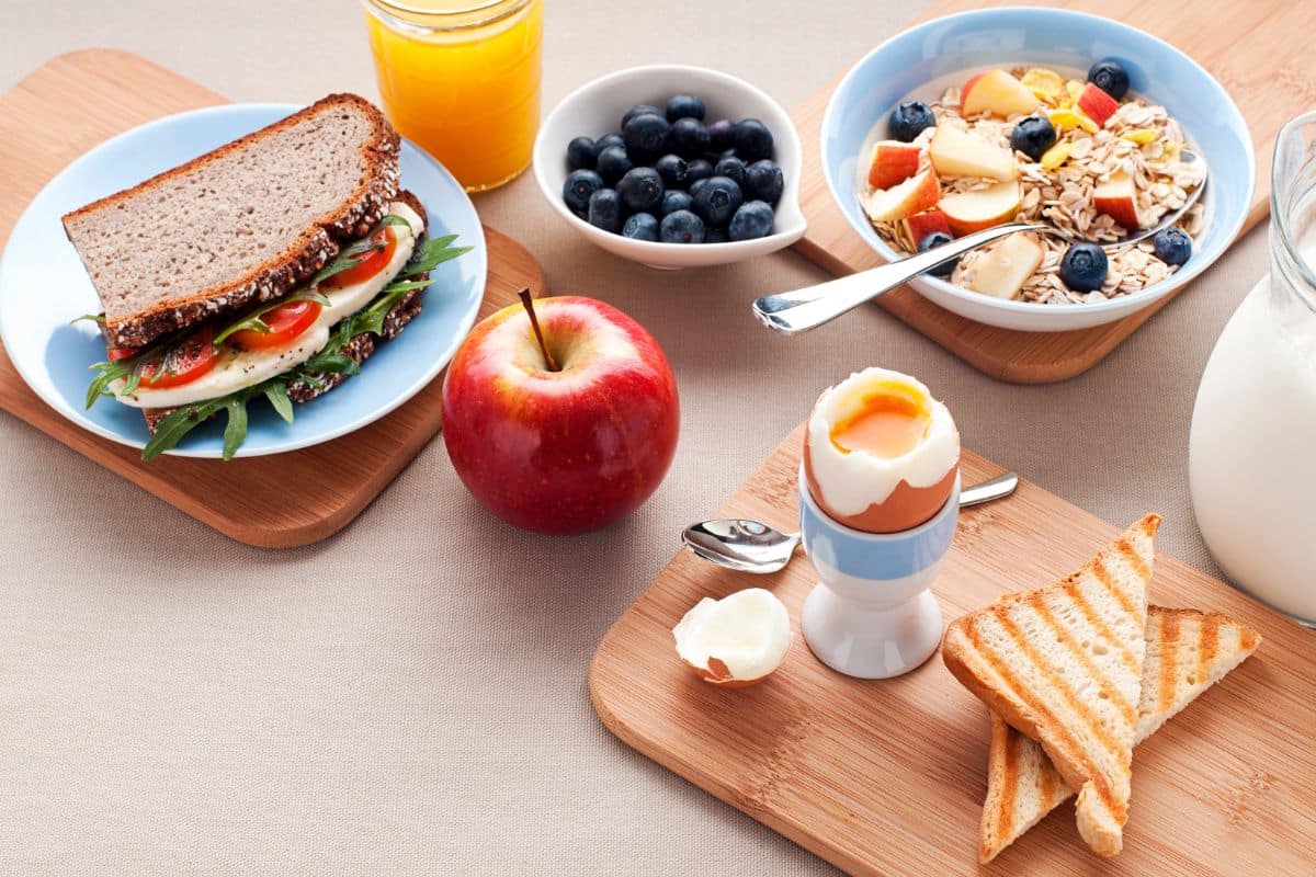 Petit déjeuner varié avec fruits, œuf et sandwich.