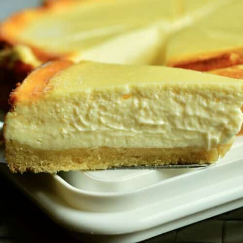 Part de cheesecake crémeux sur assiette blanche.