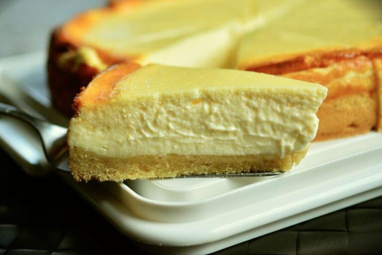 Part de cheesecake crémeux sur assiette blanche.