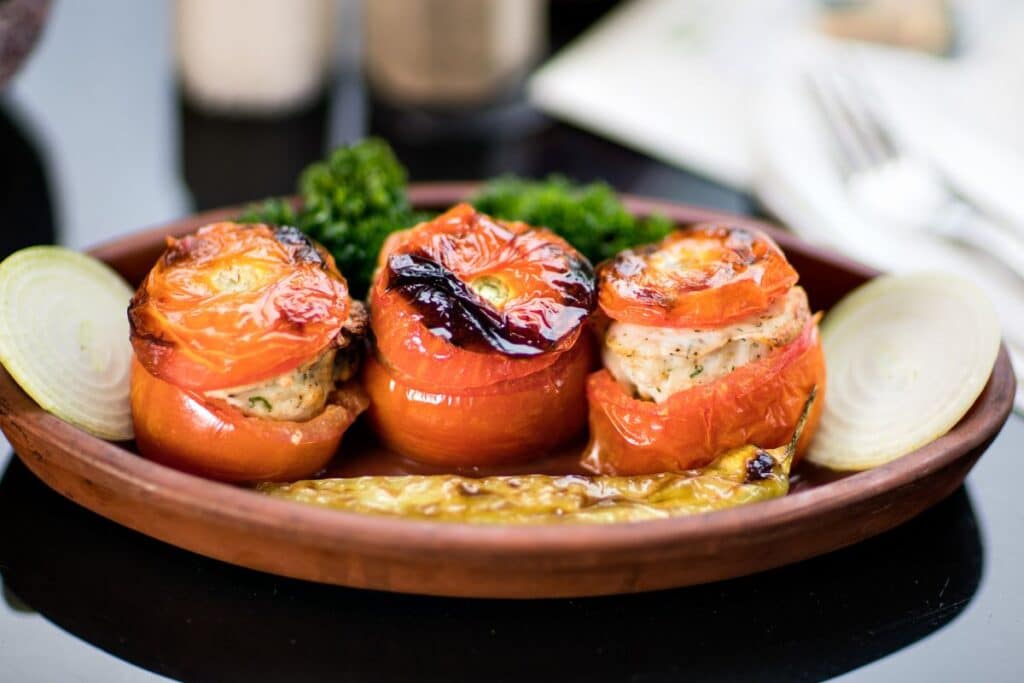 Tomates farcies sur assiette en terre cuite.
