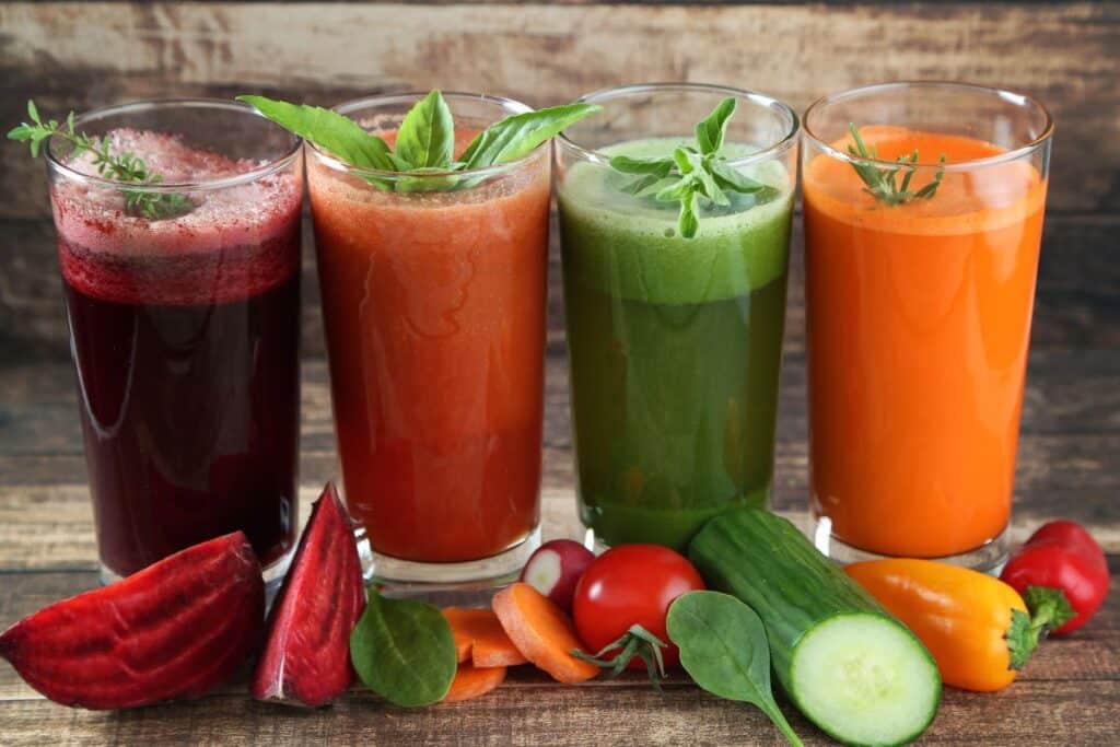 Quatre jus de légumes avec légumes frais.