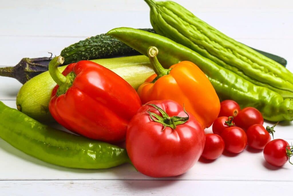 Assortiment de légumes colorés sur table blanche.