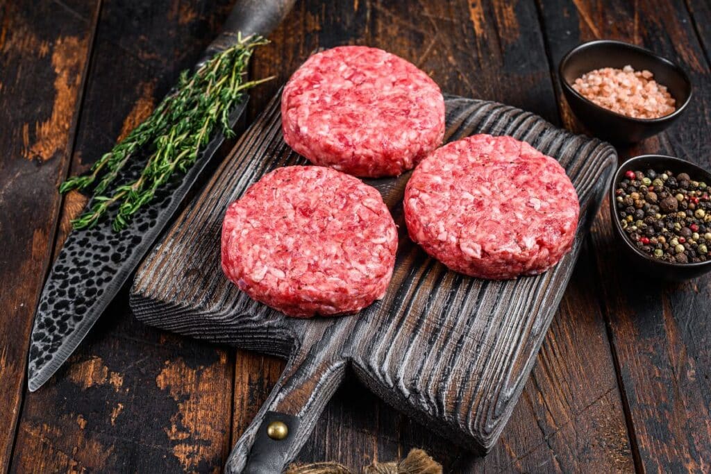 Trois steaks hachés sur planche avec épices