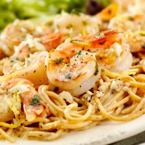 Spaghettis aux crevettes et ail sur assiette blanche.