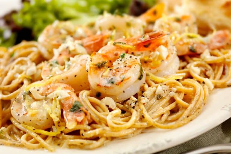 Spaghettis aux crevettes et ail sur assiette blanche.