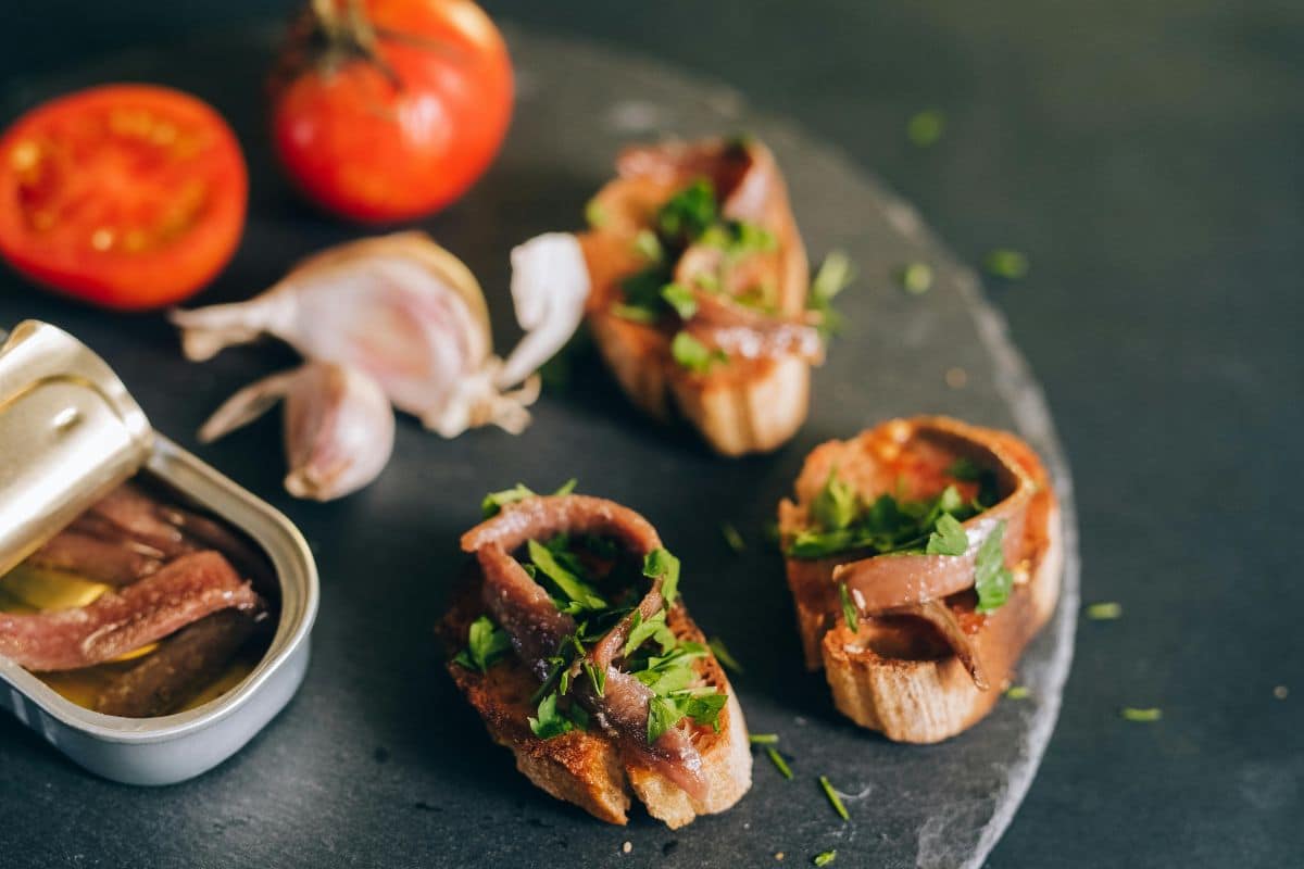 Bruschettas aux anchois et persil avec tomates.