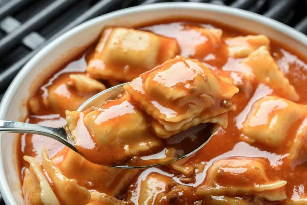 Raviolis sauce tomate sur une cuillère.