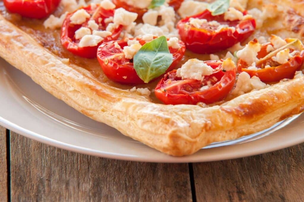 Tarte feuilletée aux tomates et fromage sur assiette.