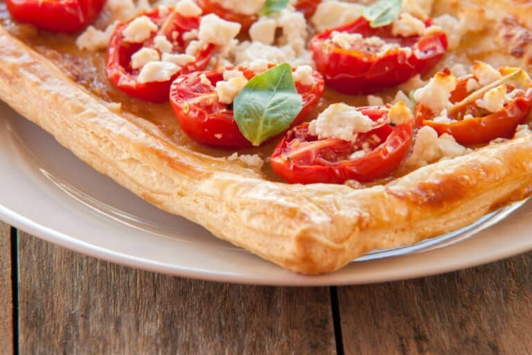 Tarte feuilletée aux tomates et fromage sur assiette.