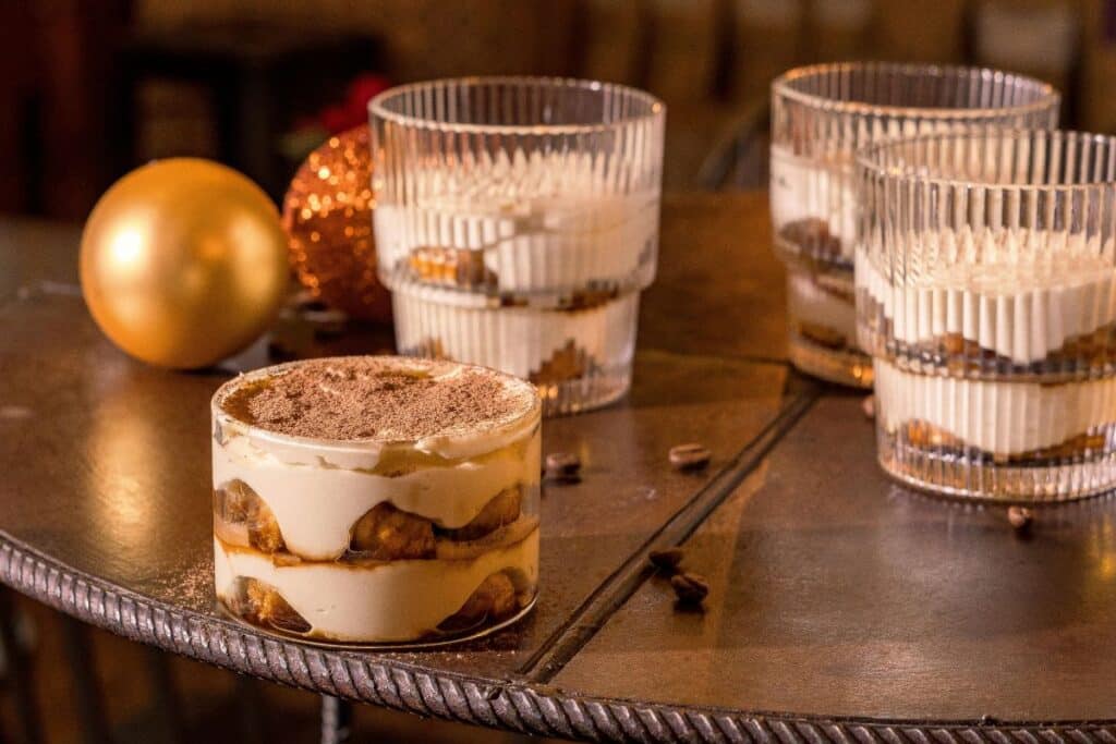 Desserts en verrines sur table avec boules dorées.