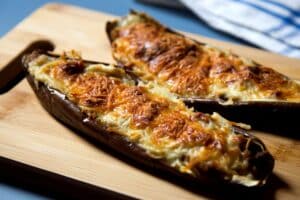 Aubergines farcies gratinées sur planche bois.