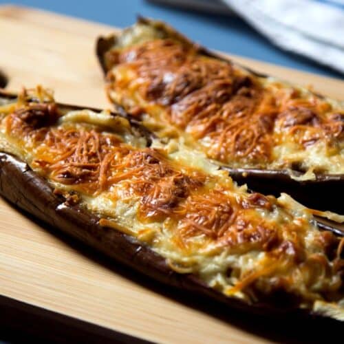 Aubergines farcies gratinées sur planche bois.