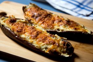 Aubergines gratinées au fromage sur planche en bois.
