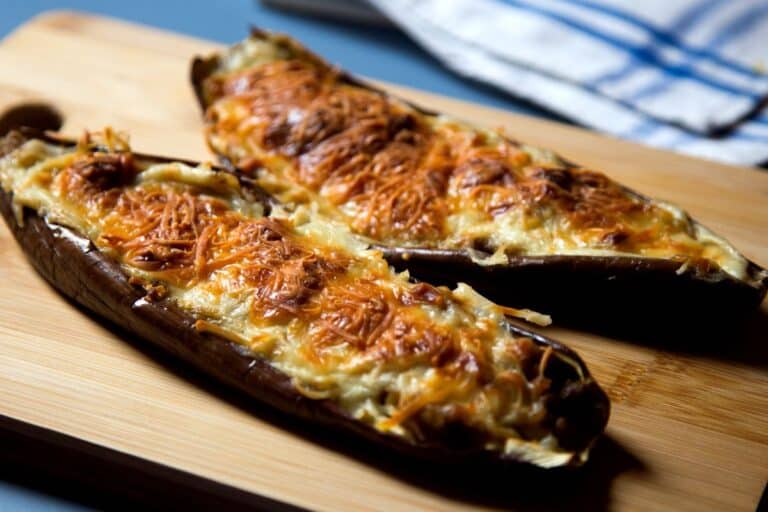 Aubergines gratinées au fromage sur planche en bois.