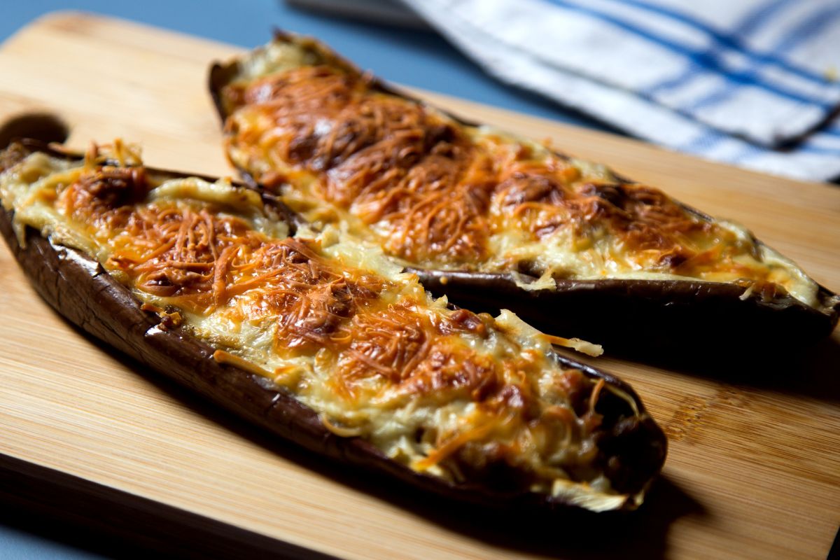 Aubergines gratinées au fromage sur planche en bois.