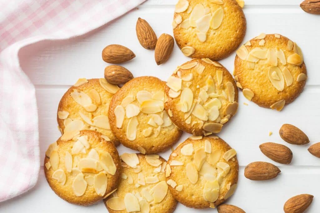 Biscuits aux amandes tranchées sur nappe rose.
