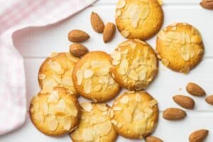 Biscuits aux amandes tranchées sur nappe rose.