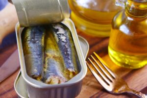 Boîte de sardines ouverte et huile d'olive.