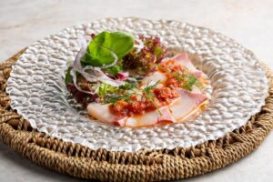 Plat de sashimi avec salade et garniture épicée.