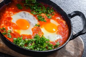 Shakshuka avec œufs et persil dans une poêle.