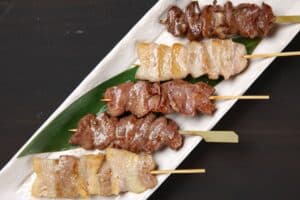 Brochettes de viande grillées sur assiette blanche.