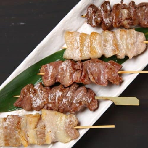 Brochettes de viande grillées sur assiette blanche.