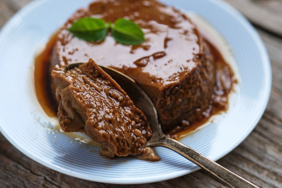 Flan au caramel sur assiette blanche, cuillère visible.