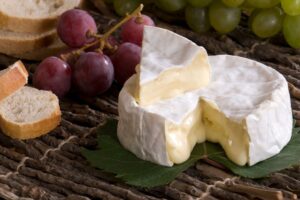 Camembert, raisins et pain sur nappe en lin.