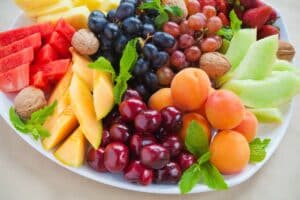Plateau de fruits variés avec noix et menthe.