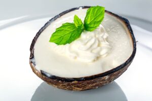 Noix de coco avec crème et menthe, fond blanc.