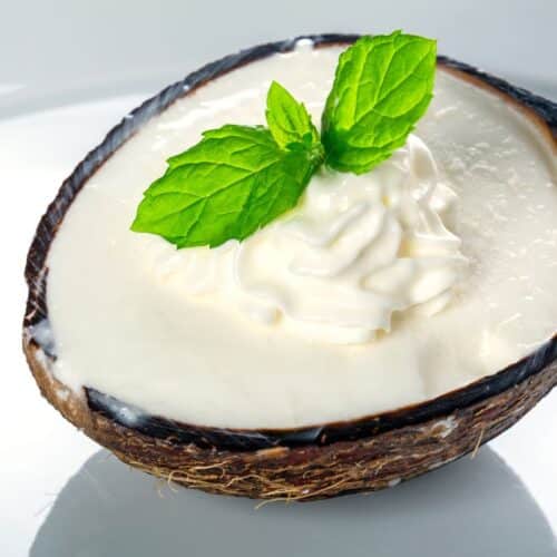 Noix de coco avec crème et menthe, fond blanc.