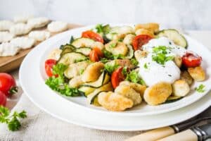 Assiette de gnocchis aux légumes frais et sauce blanche.