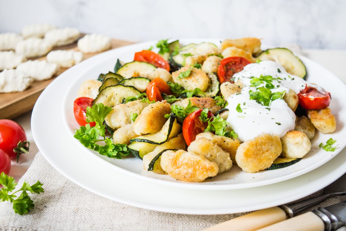 Assiette de gnocchis aux légumes frais et sauce blanche.